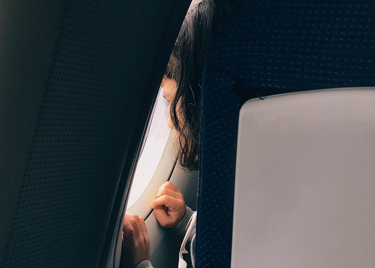 Ребенок смотрит в иллюминатор самолета