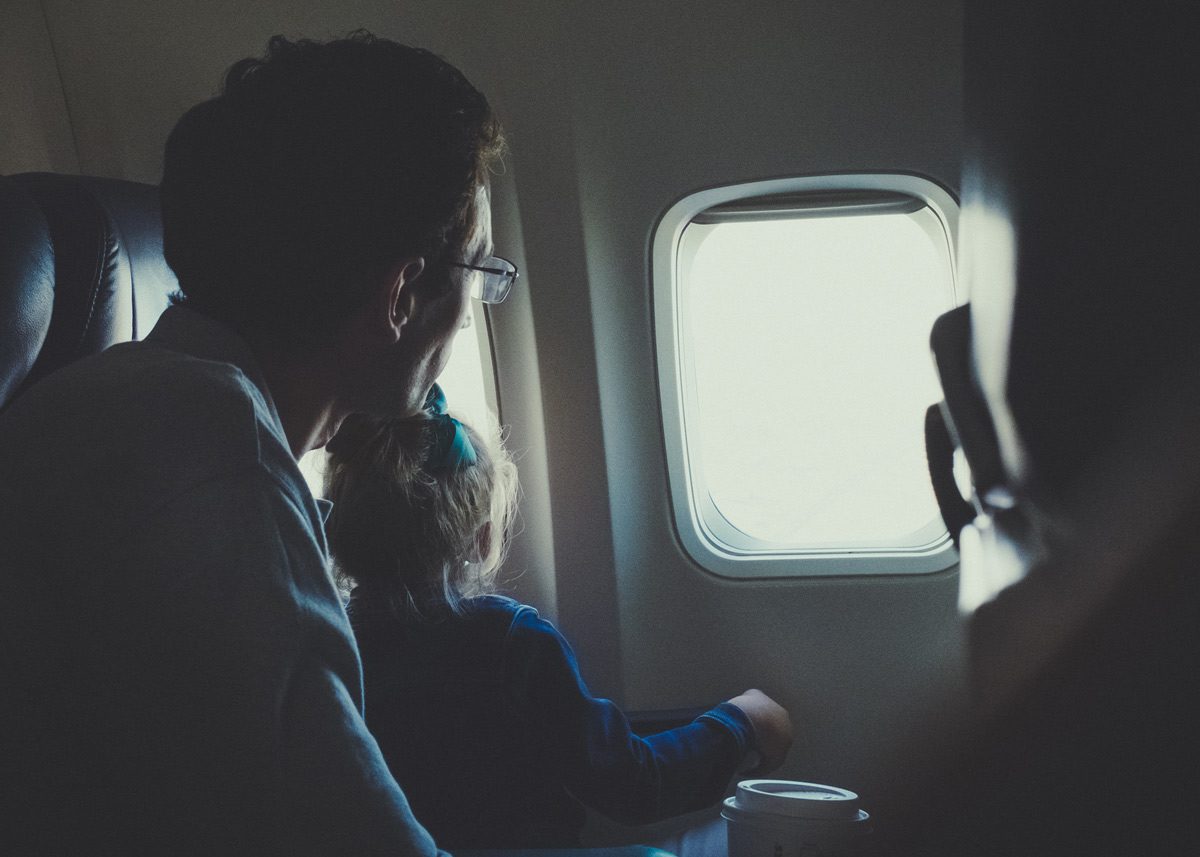 Девочка и мужчина смотрят в иллюминатор самолёта