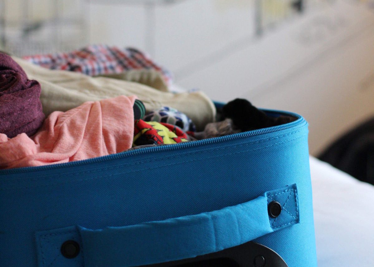 Одежда лежит в синем чемодане