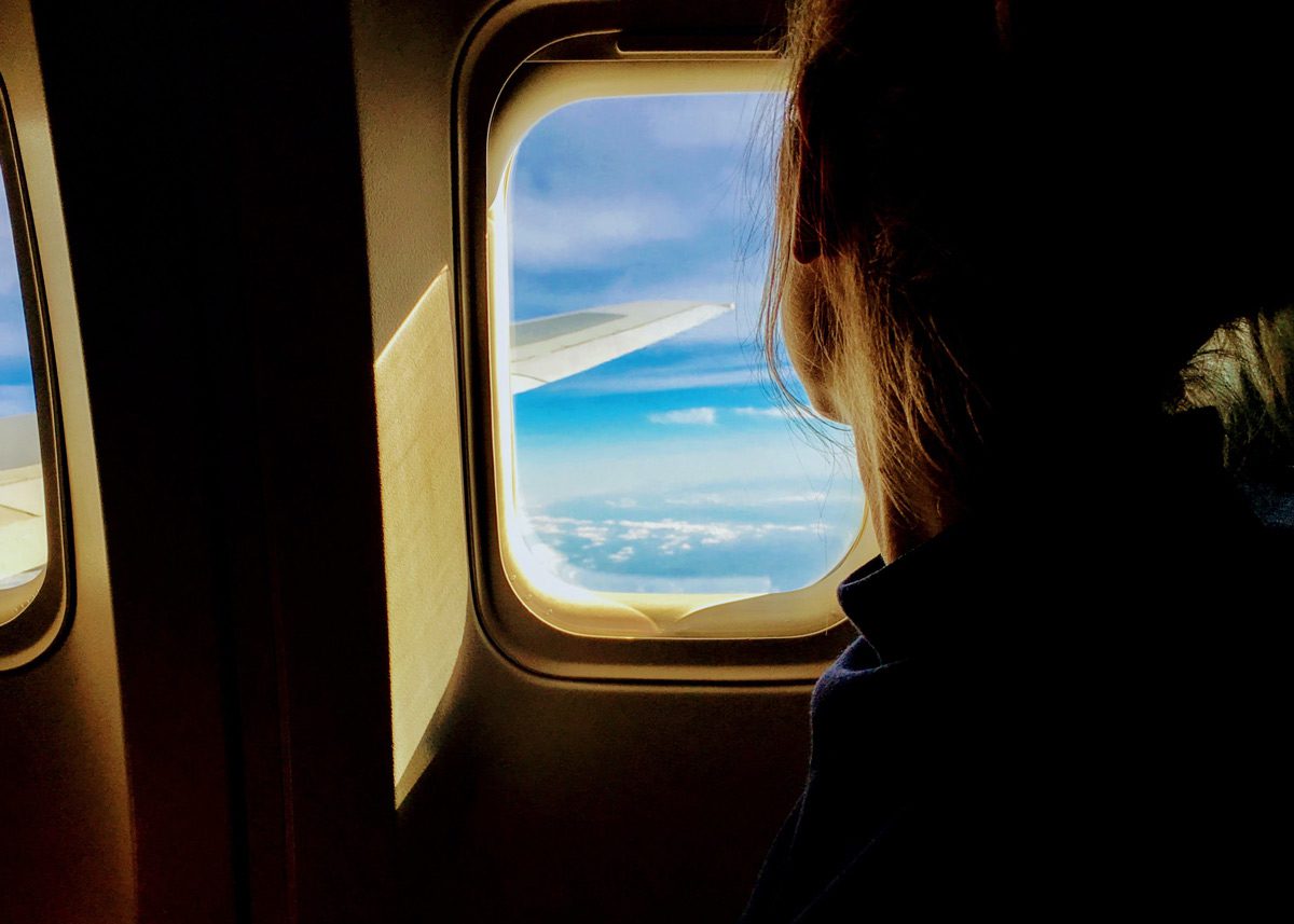 Девушка смотрит в иллюминатор самолёта