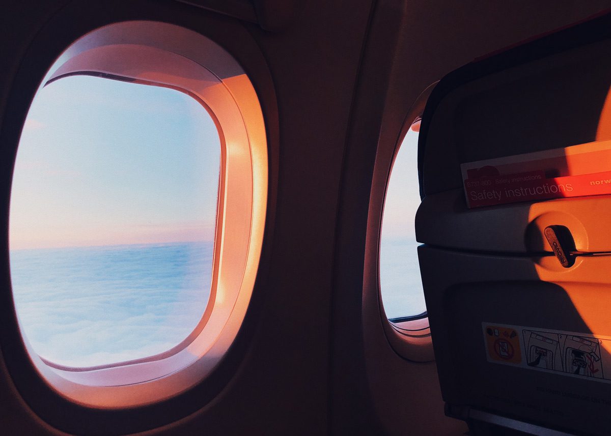 Проходящие через иллюминатор лучи закатного солнца в салоне самолёта