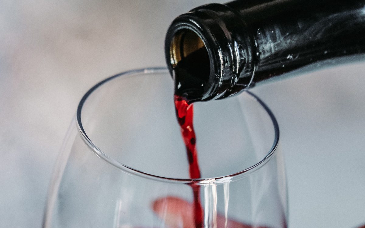Красное вино наливают в прозрачный бокал