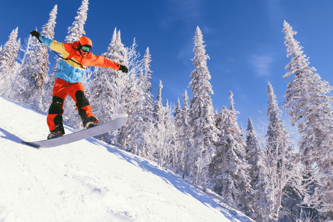 Человек скатывается с горы на сноуборде