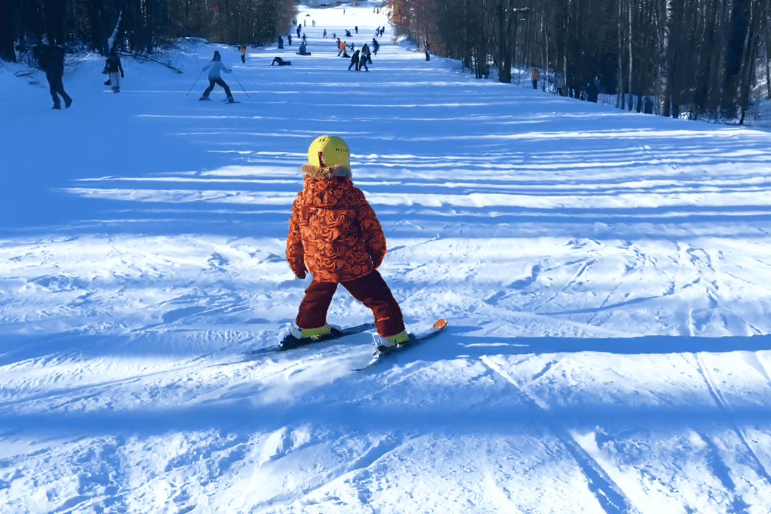 Ребенок стоит на лыжах перед горным склоном