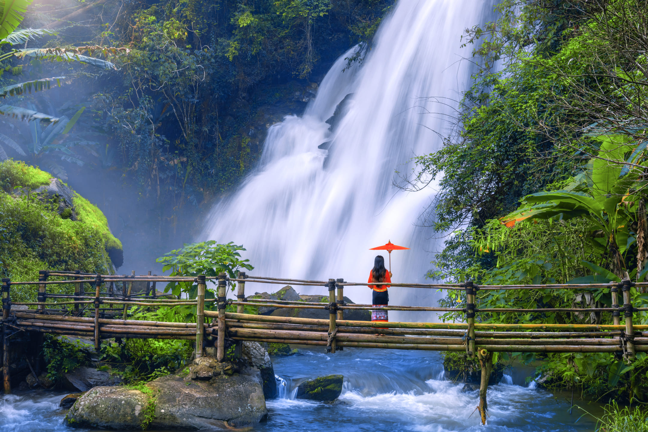 Девушка с зонтом напротив водопада