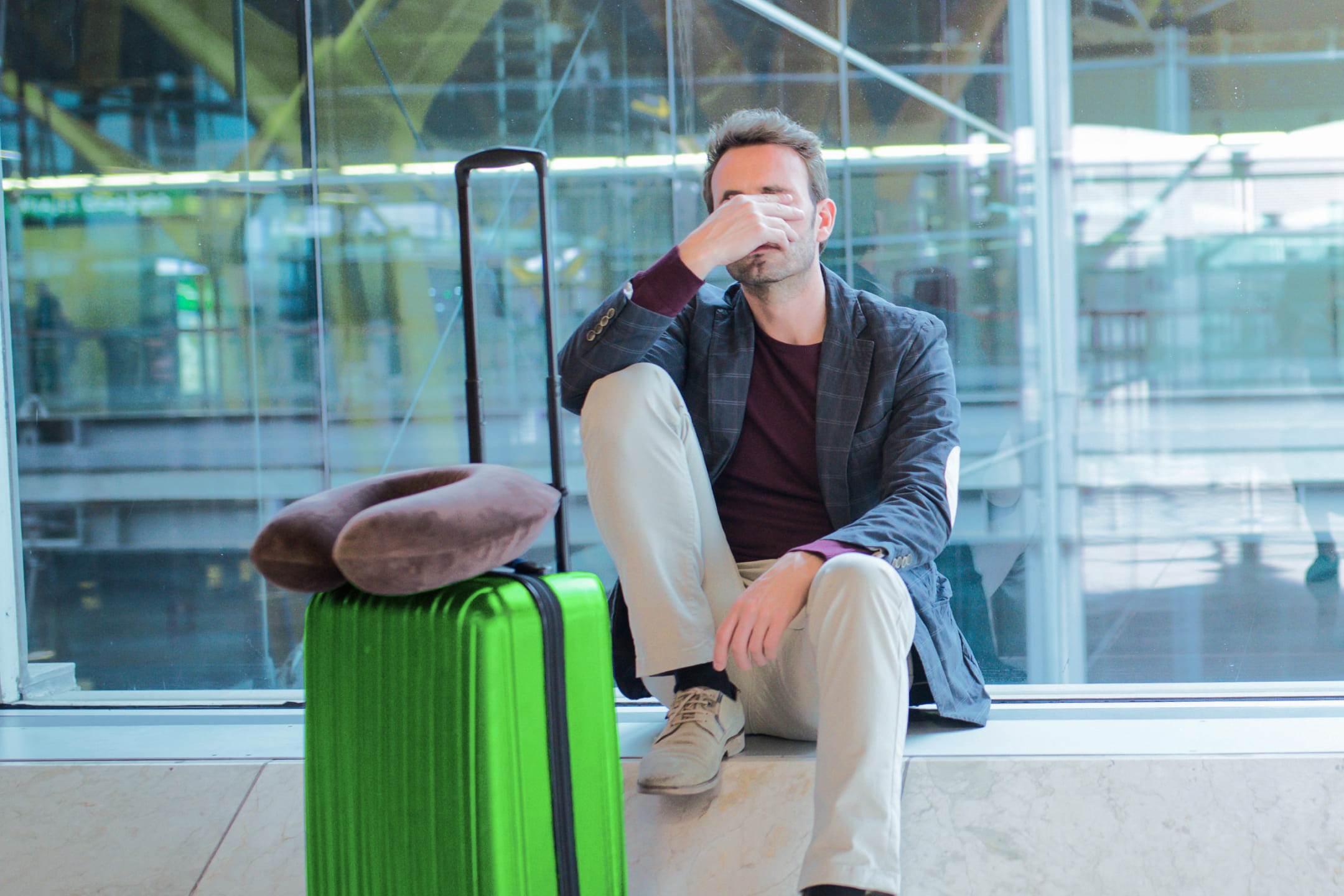 Мужчина с зеленым чемоданом в аэропорту